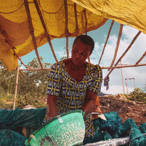 Woman using a bowl under a bamboo structure covered by a bright yellow canopy