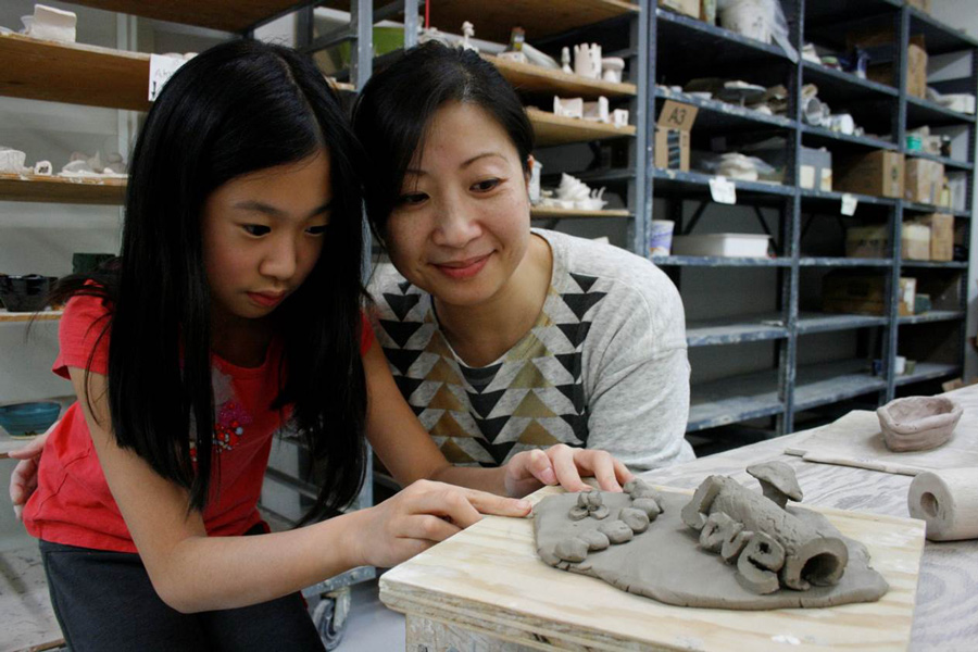 Asian_Mother_And_Daughter_Looking_At_Clay_Project_In_Art_Studio