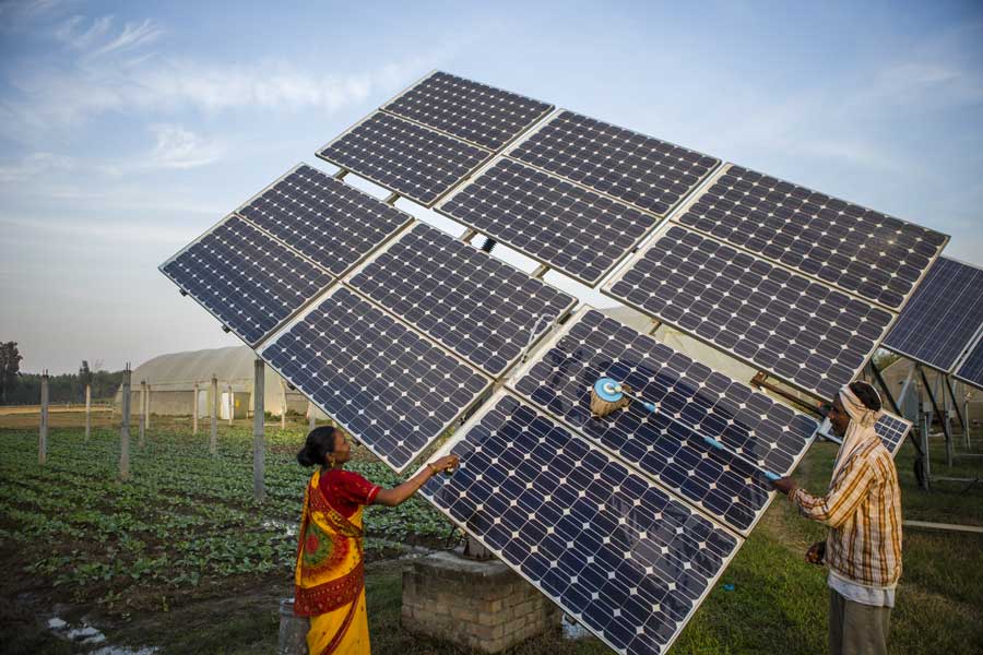 A woman and a man cleaning solar panels.