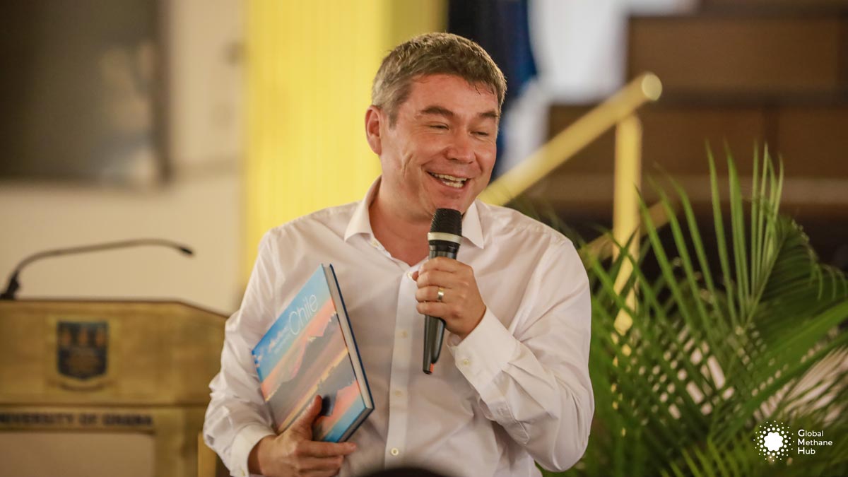 A man in a white shirt with a book in one hand and a microphone in the other hand.