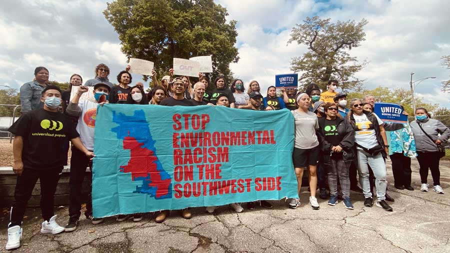 a group of people standing in front of a banner that says Stop Environmental Racism on the Southwest Side.
