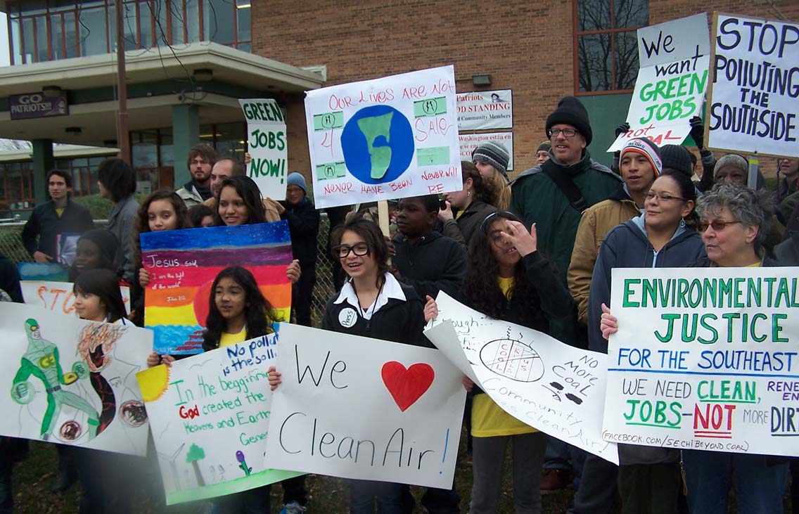 a group of kids and some adults holding handmade signs with environmental messages